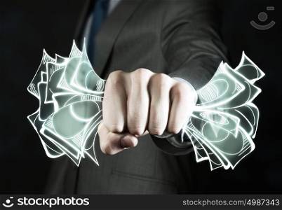 Business power. Close up of businessman grasping dollar banknotes in fist