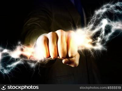 Business power. Close up of businessman grasping lightning in hand
