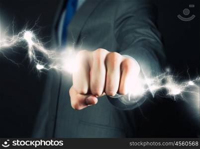 Business power. Close up of businessman grasping lightning in hand