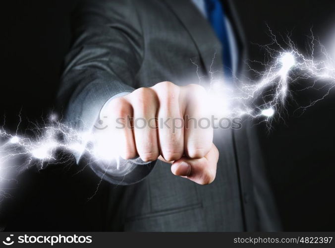 Business power. Close up of businessman grasping lightning in hand