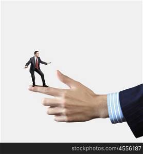 Business power. Young businessman balancing on finger of businessman