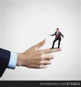 Business power. Young businessman balancing on finger of businessman