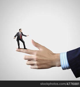 Business power. Young businessman balancing on finger of businessman