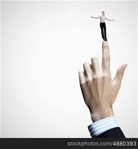 Business power. Young businesswoman balancing on finger of businessman