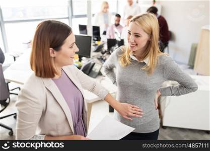 business, pregnancy and people concept - happy colleague touching pregnant woman belly at office