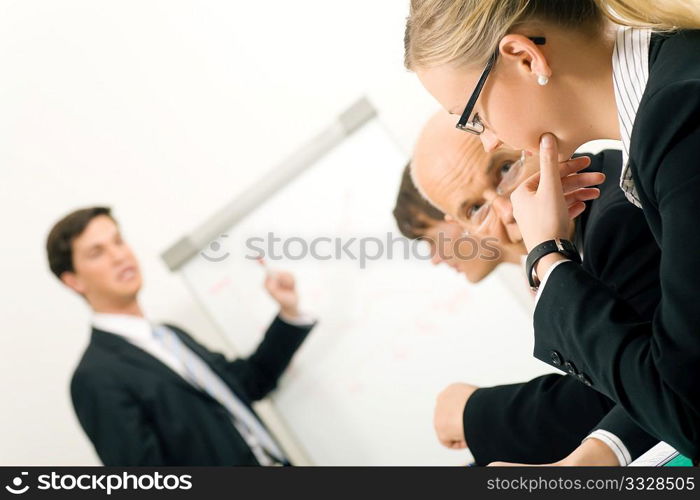 Business Presentation at flipchart in office, two participants discussing. Very selective focus! Focus only on face of woman in front.