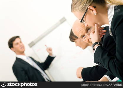 Business Presentation at flipchart in office, two participants discussing. Very selective focus! Focus only on face of woman in front.