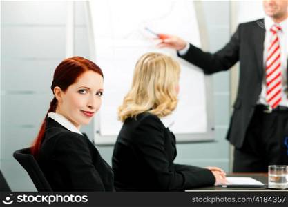 Business - presentation within a team; a colleague is standing on the flipchart
