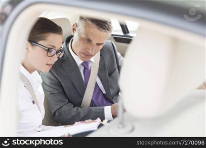 Business professionals discussing over documents while sitting in car