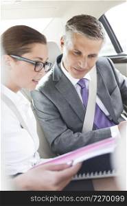 Business professionals discussing over laptop and documents while sitting in car