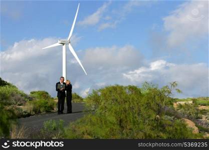 Business professionals standing before a wind turbine
