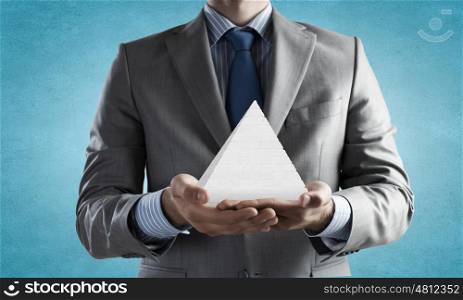 Business pyramid. Close up of businessman holding pyramid in hands
