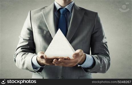 Business pyramid sysytem. Close up of businessman holding pyramid in hands