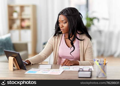 business, remote job and technology concept - african american female ui designer with tablet pc computer working on user interface design at home office. african woman working on ui design at home office