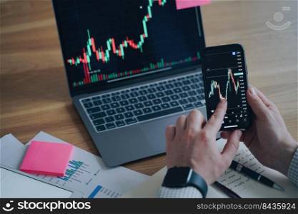 Business report. Financial diagram is on laptop and smartphone screens. Man is working on the deal in office. Mobility and Online trading. Display of PC and phone on the desk. Startup development.. Business report. Financial diagram is on screens. Man is working on the deal. Startup development.