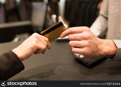 business, sale, payment and people concept - close up of customer hand giving credit card to seller or bank manager