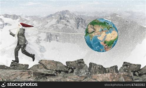 Business Santa. Businessman in Santa hat pulling Earth planet with rope. Elements of this image are furnished by NASA