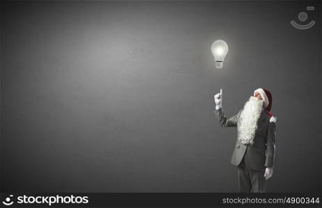 Business Santa. Thoughtful businessman in Santa pointing at light bulb