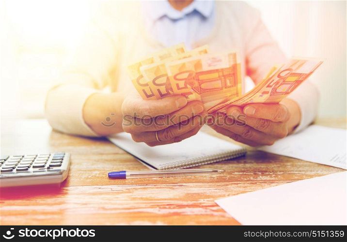 business, savings, annuity insurance, age and people concept - close up of senior woman with calculator and bills counting euro money at home. close up of senior woman counting money at home