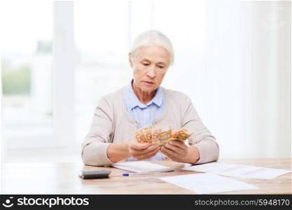 business, savings, annuity insurance, age and people concept - senior woman with calculator and bills counting euro money at home