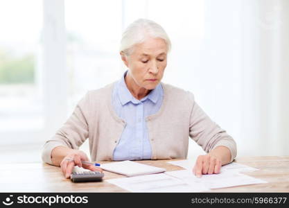 business, savings, annuity insurance, age and people concept - senior woman with papers or bills and calculator writing at home