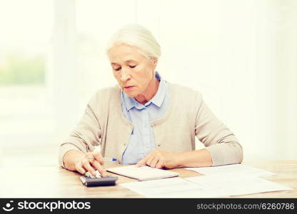 business, savings, annuity insurance, age and people concept - senior woman with papers or bills and calculator writing at home