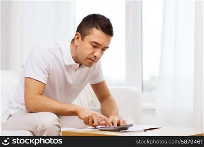 business, savings, finances and people concept - man with papers and calculator at home
