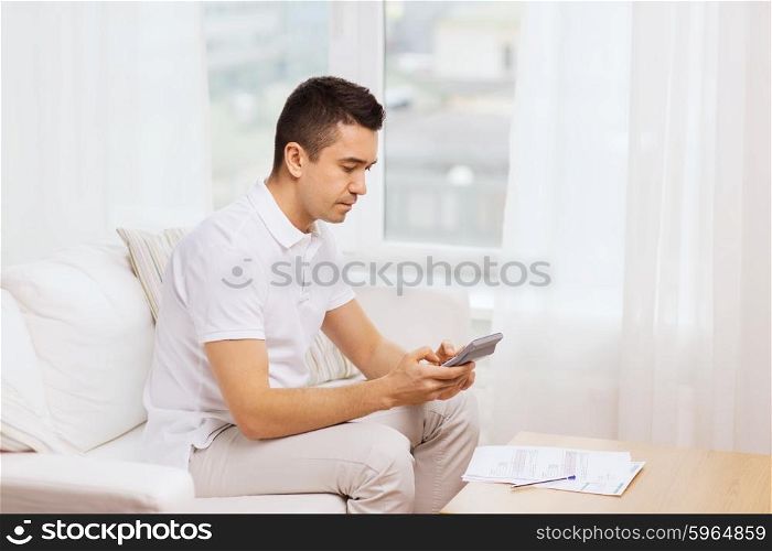 business, savings, finances and people concept - man with papers and calculator at home
