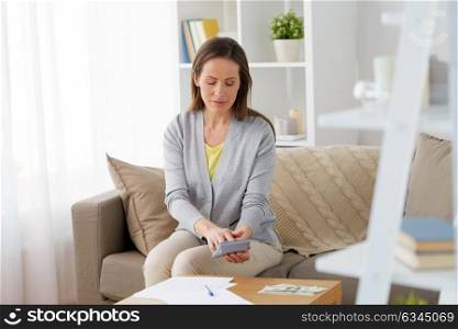 business, savings, finances and people concept - middle-aged woman with money, papers and calculator at home. woman with money, papers and calculator at home