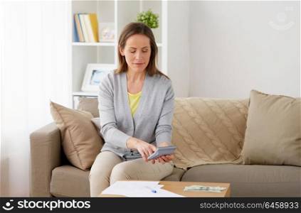 business, savings, finances and people concept - middle-aged woman with money, papers and calculator at home. woman with money, papers and calculator at home