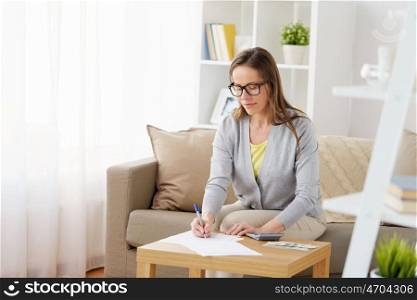 business, savings, finances and people concept - middle-aged woman with papers, money and calculator at home. woman with papers, money and calculator at home. woman with papers, money and calculator at home
