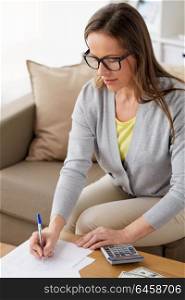 business, savings, finances and people concept - middle-aged woman with papers, money and calculator at home. woman with papers, money and calculator at home