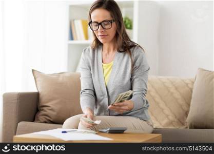 business, savings, finances and people concept - woman with papers and calculator counting money at home. woman with money, papers and calculator at home