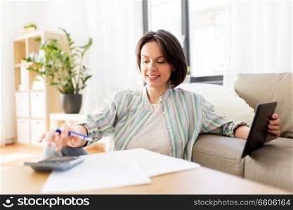 business, savings, finances and people concept - woman with tablet pc, papers and calculator at home. woman with tablet pc, bills and calculator at home