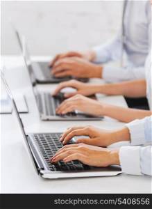 business, school and education concept - group of people working with laptops in office