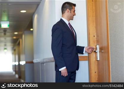 business, security and people concept - businessman with keycard at hotel room or office door. businessman with keycard at hotel or office door