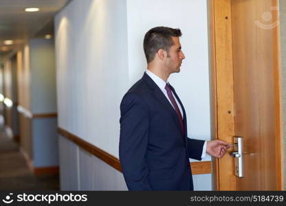 business, security and people concept - businessman with keycard at hotel room or office door. businessman with keycard at hotel or office door