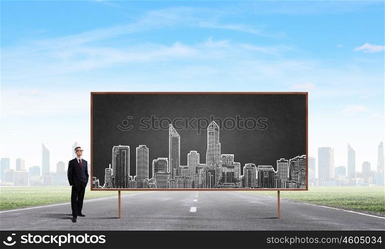 Business seminar. Young confident man wearing glasses standing near blackboard