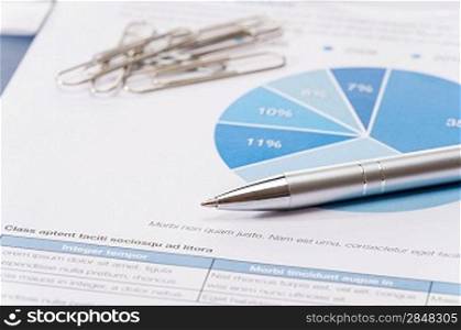 Business silver pen over office paper charts close-up