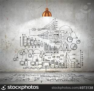 Business sketch on wall. Drawn business plan on wall illuminated by lamp above