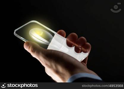 business, solution, idea, people and future technology concept - close up of businessman hand with lightbulb on transparent smartphone screen over black background. close up of hand with lightbulb on smartphone
