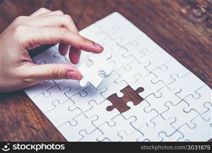 Business solutions, success and strategy concept. Businessman hand connecting jigsaw puzzle.
