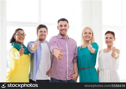 business, startup and office concept - happy creative team showing thumbs up in office