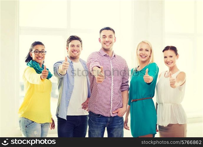 business, startup and office concept - happy creative team showing thumbs up in office