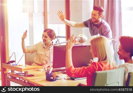 business, startup and office concept - happy creative team waving hands in office