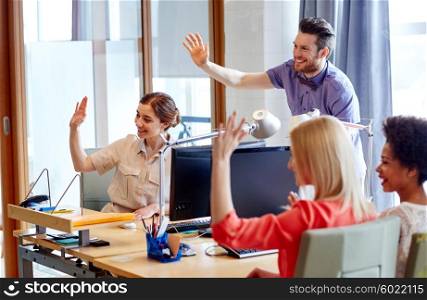 business, startup and office concept - happy creative team waving hands in office