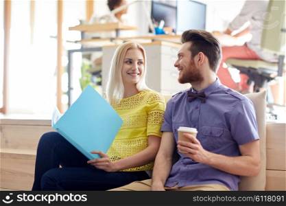 business, startup and people and concept - happy man and woman with folder drinking coffee and talking in office