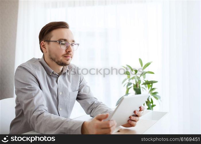 business, startup and people concept - businessman or creative male office worker with tablet pc computer at home office