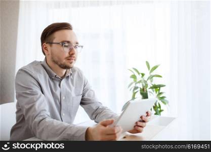 business, startup and people concept - businessman or creative male office worker with tablet pc computer at home office