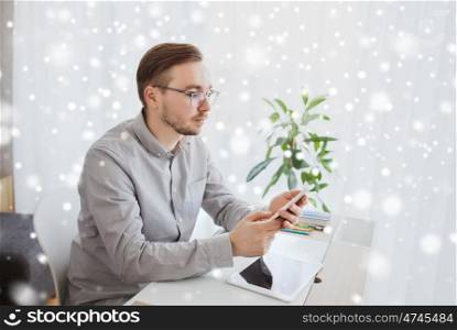 business, startup and people concept - businessman or creative male worker texting on smarphone at home office over snow